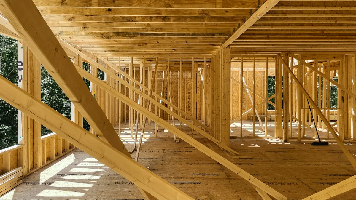 Exposed timber framing, floor joists, and window openings in a home under construction