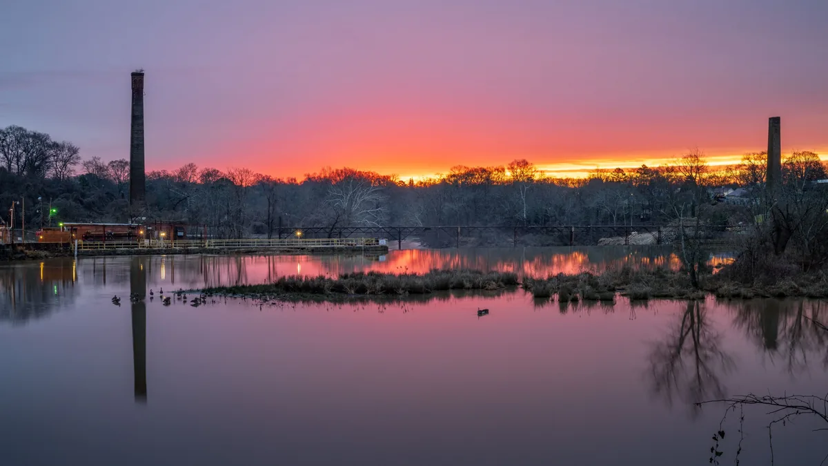 Sunset reflected on the river in Piedmont, South Carolina, with a bridge and brick mill chimneys