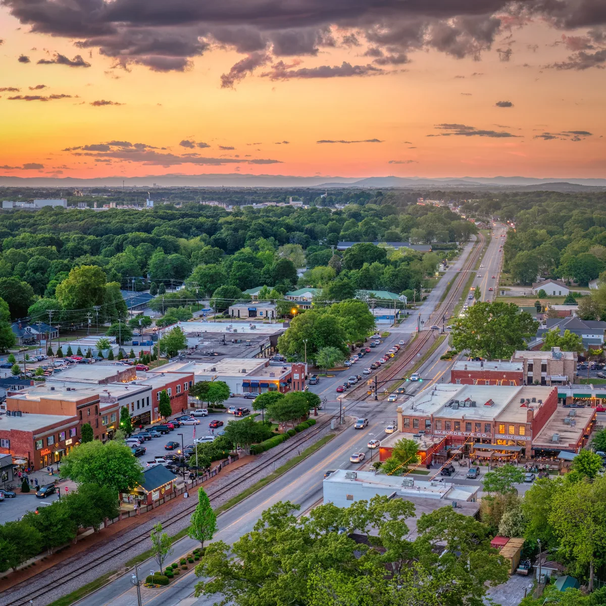 Sunset aerial over downtown Simpsonville, with Main Street, the railroad, and storefronts below